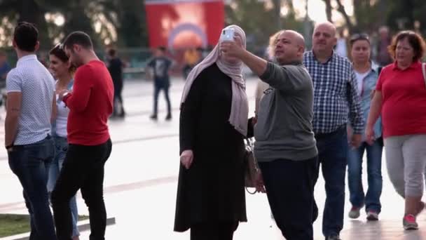 混雑した街の通りに立っているスマートフォンを使用して一緒に自撮りイスラム教徒のカップル. — ストック動画