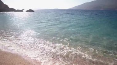 Kumlu sahilde deniz dalgaları olan manzaralı bir yer..