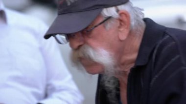 Uzun gri bıyıklı yaşlı adam bulanık arka planda yemek yiyor..