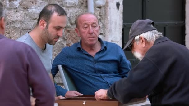 Hombres sentados en la cafetería al aire libre y jugando backgammon. — Vídeos de Stock