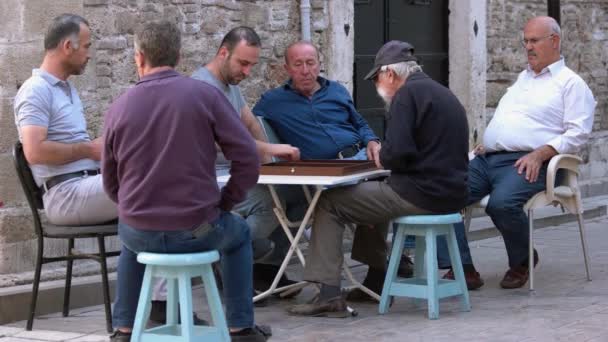 Férfiak csoportja a szabadban ül és backgammon játékot játszik. — Stock videók