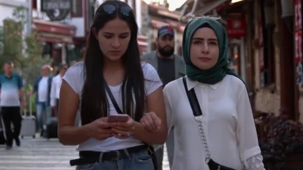 Woman walking while looking at cellphone. Tourists exploring the city. — Stock Video