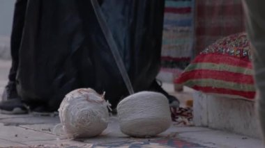 Erkek işçi sokak pazarında iplik toplarını çantaya koyuyor. El yapımı endüstri.