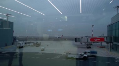 Havaalanı terminalinde hızlı hareket eden yolcu uçağı ve araçlar..