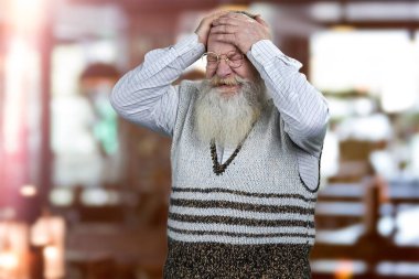 Çaresiz yaşlı adam hayal kırıklığından başını tutuyor. Görüntü arkaplanı.