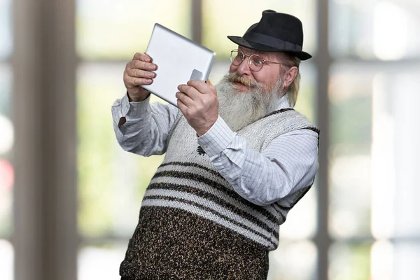 Zabawny starszy mężczyzna za pomocą tabletu cyfrowego i wygląda na zaskoczonego. — Zdjęcie stockowe