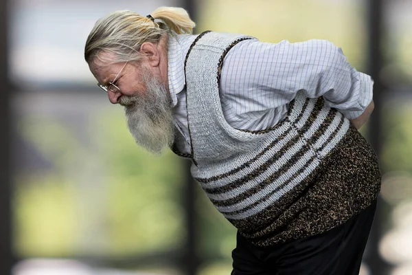 Vue latérale du vieil homme barbu souffrant de maux de dos. — Photo