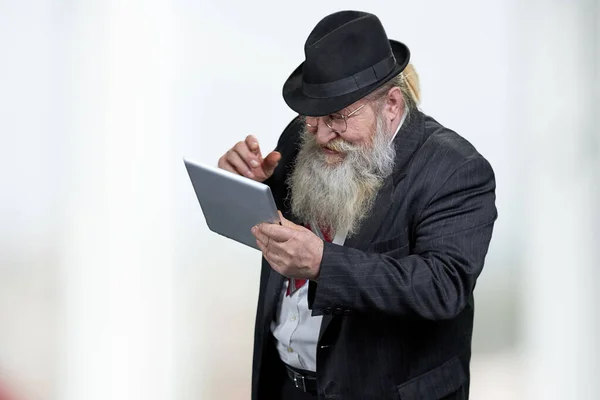 Radosny starszy mężczyzna w klasycznym czarnym kapeluszu za pomocą tabletu cyfrowego. — Zdjęcie stockowe