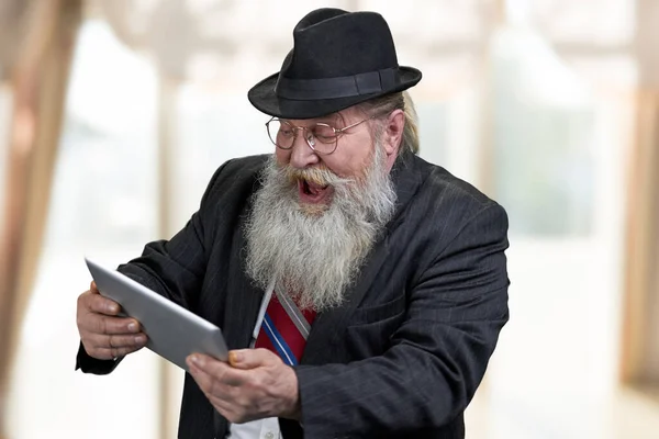 Cheerful senior man in suit having fun using digital tablet. — Stock Photo, Image