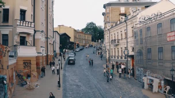 Cobblestone descent road with walking people and historical houses. — Stock Video