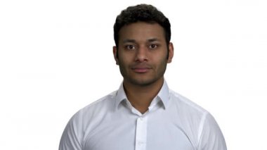 Beyaz gömlekli, gülümseyen adam kameraya bakıyor..