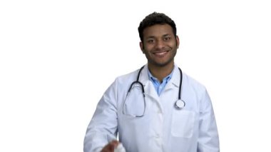 Doktor hapları ve kameraya başparmağını gösteriyor..