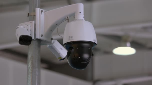 Close-up rotating black surveillance control camera indoors. — Stock video
