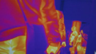 Infrared thermal vision of people walking indoors.