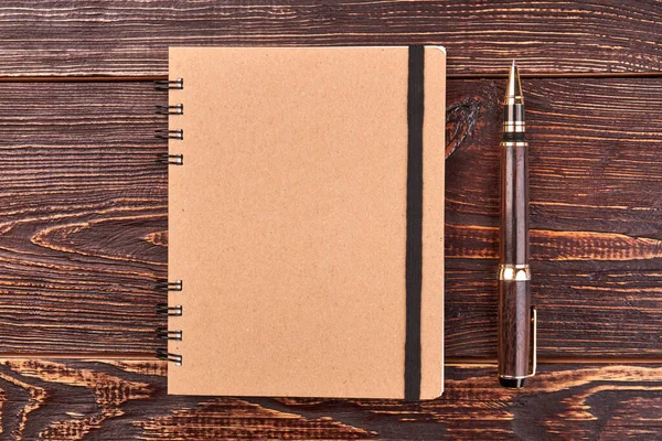 Notepad and pen on brown wooden desk. — Stok fotoğraf