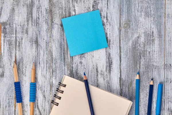 Blank blue sticky note with pencils and notepad. — Stok fotoğraf