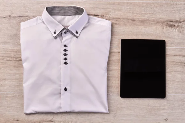 Top view of white folded shirt and tablet device. — Stockfoto