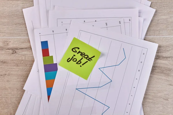Sticky note with great job handwriting and charts with statistic. — Fotografia de Stock