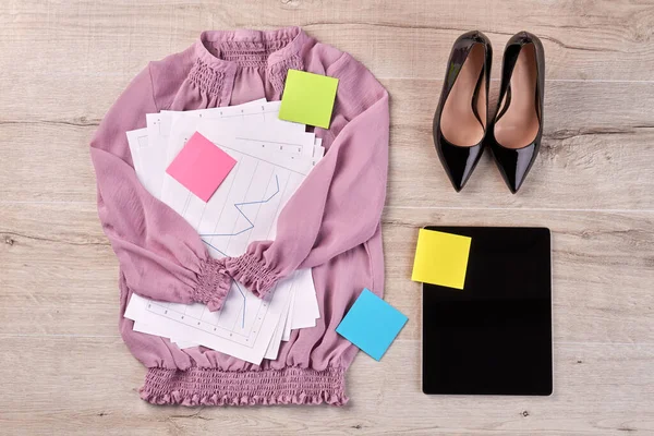 Purple blouse with work papers and black shoes.