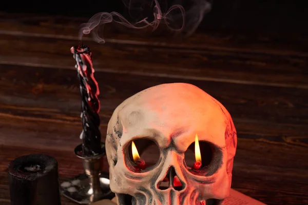 Emberi koponya lánggal a szemében és füsttel oltott gyertyák.. — Stock Fotó