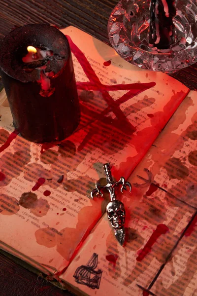 Vertical shot of antichrist cross on the satanic bible stained with blood. — Stock Photo, Image