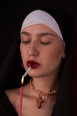 Kötü bir genç rahibenin portresi kilise mumuyla bir sirarette yakıyor..