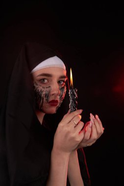 Genç gotik satanist bir kızın portresi yanan bir mum tutuyor..