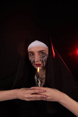 Genç gotik bir kızın portresi karanlıkta yanan bir mum tutuyor..