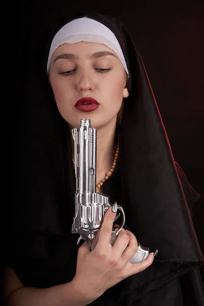Portret van een jonge non die haar zilveren revolver opblaast na het schieten. — Stockfoto