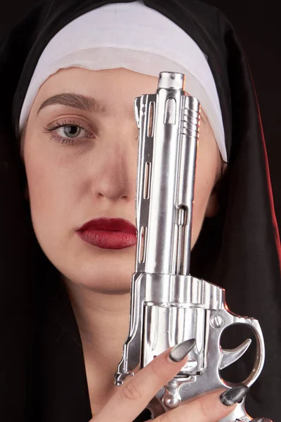 Close-up portret van een non houdt zilveren revolver pistool omhoog. — Stockfoto