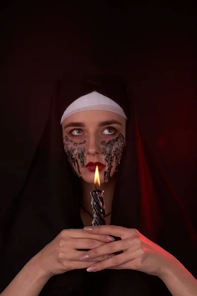 Egy hátborzongató sátánista lány portréja mindkét kezében gyertyát tart.. — Stock Fotó