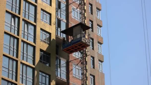Arbeiter fahren mit dem Aufzug auf der Baustelle nach unten. — Stockvideo