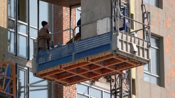 Les travailleurs de la construction descendent sur l'ascenseur. — Video