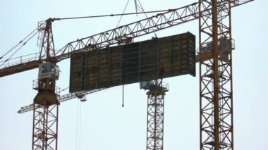 Sarı vinç büyük beton blok taşır.