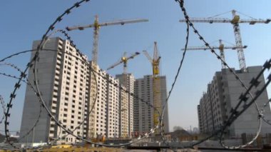 Arka planda yakın plan dikenli tel ve gökdelen inşaatı.