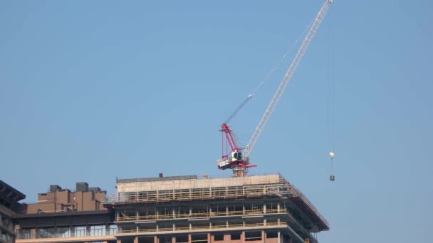 Dźwig budowlany przenoszący blok na szczycie budynku. — Wideo stockowe