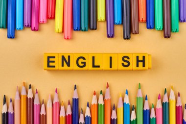 Renkli okul malzemelerinin çerçevesinde plastik küplere yazılmış ENGLISH kelimesi. Düz konum.