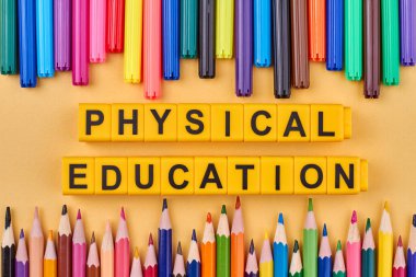 Sarı küplerin üzerine yazılan beden eğitimi yazıları renk arkaplanına karşı. Düz yatıyordu.