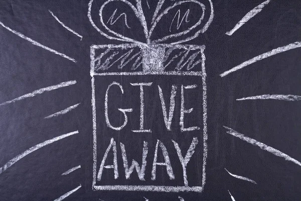 Give away handwritten inscription with white chalk on black chalkboard. Promotion concept.