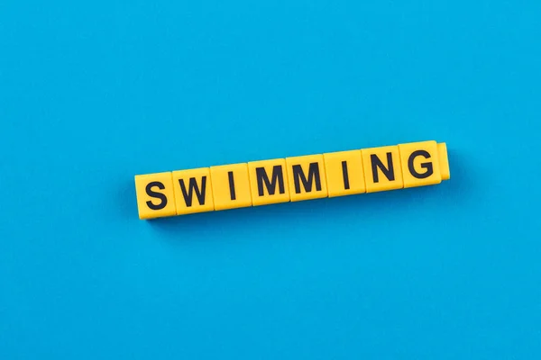 Woord Zwemmen Geschreven Gele Kubussen Tegen Een Blauwe Achtergrond Vlakke — Stockfoto