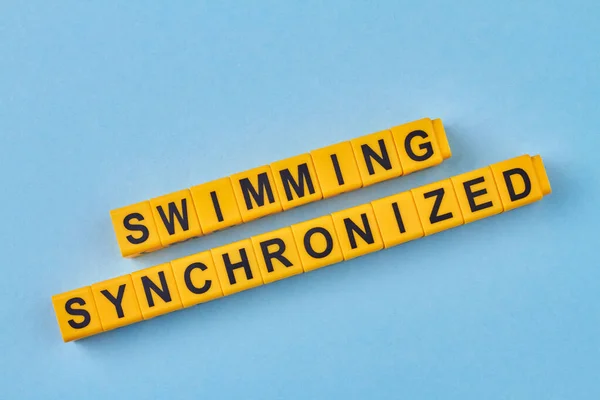 青を背景に黄色の立方体に書かれた碑文水泳同期 競技に由来する競泳練習又は展示 — ストック写真