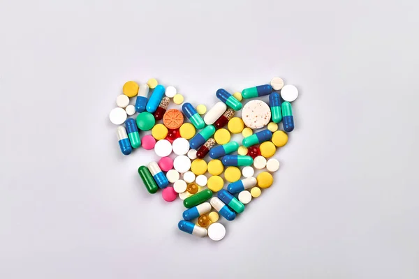 Heart of pills and capsules isolated on white background. Top view flat lay.