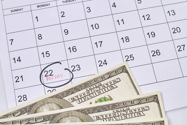 Close-up marked pay day and dollars on the calendar. 22 day of month.