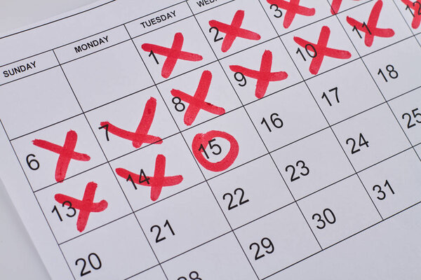 Paper calendar with red crosses and circle closeup-up. Business appointment concept.