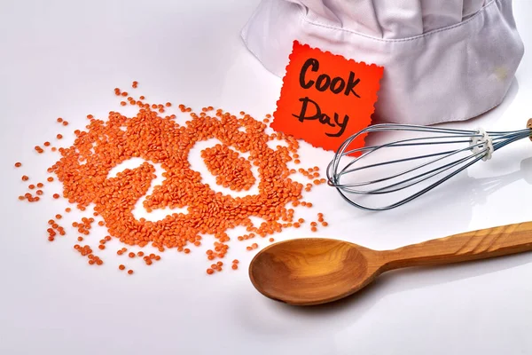 Cook day concept. Pile of lentils in the shape of number 20. Wooden spoon and mixer tool on white background.