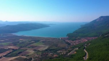 Dağlarda mavi deniz ve tarlalar olan güzel doğa manzarası. Şehir binaları ve dağların arasında deniz olan vadinin üst manzarası..