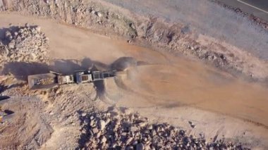 Asfalt yolunun yakınındaki inşaat alanında çalışan ağır makinelerin hızlı hareketi. Yukarıdan üst görünüm.