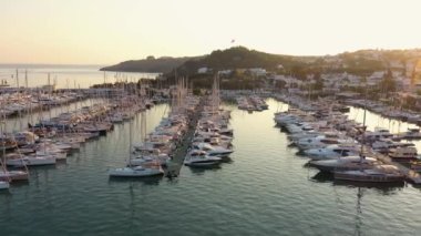 Gemileri demirli olan deniz limanı manzarası ve arkasında güzel bir günbatımı gökyüzü olan Bodrum şehri. Akdeniz kıyısındaki tatil köyü.