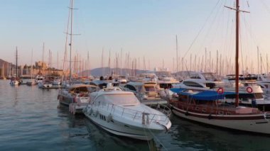 Marina, Bodrum, Türkiye. Sakin Ege Denizi 'nde demirlemiş tekneleri olan bir liman. Arka planda güzel gün batımı gökyüzü.