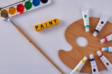 Beyaz arka planda boya fırçasıyla resim yapmak için üst görünüm paletleri. Yağ tüplerinin düzenlenmesi.